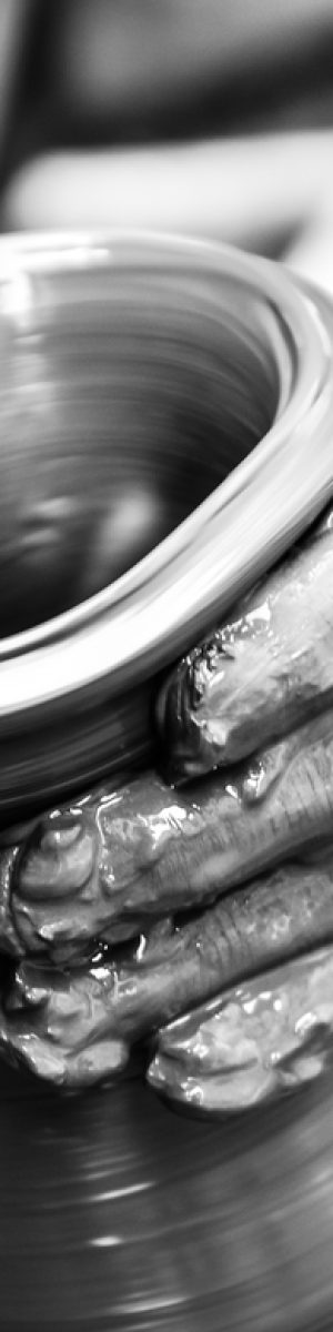 Hands of a man creating pottery on wheel, monochrome vintage view